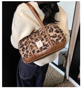 Detail of leopard print faux fur shoulder bag with soft brown leather handles and brand tag