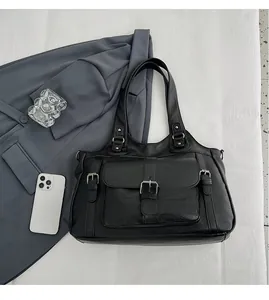 Detail of black pebbled leather tote bag with functional buckle pockets for daily commute