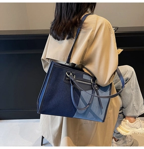 Close-up of color-block tote bag showing blue canvas texture and leather handles