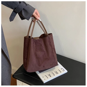 Détail de la texture en daim marron chocolat et des poignées en cuir du sac fourre-tout