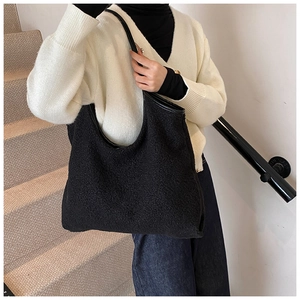 Detail of black faux shearling tote bag with contrasting leather shoulder strap and trim