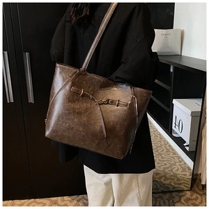 Detail of vintage dark brown waxed leather tote bag with decorative side zipper and buckle