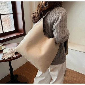 Detailed back view of a beige matte leather hobo bag worn by a model in a cozy interior