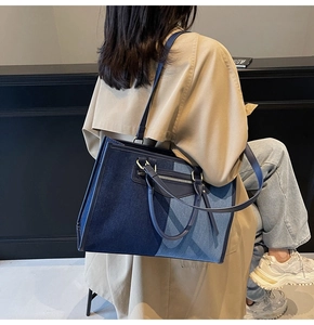 Blue patchwork canvas tote bag shown on model with shoulder strap and metal zipper detail