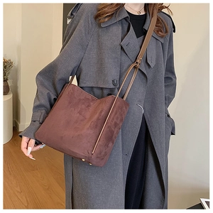Sac fourre-tout minimaliste marron foncé porté avec un trench-coat montrant les détails