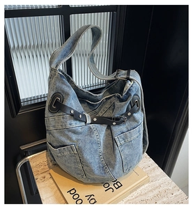 Detail of vintage blue denim messenger bag with leather straps and metal buckles