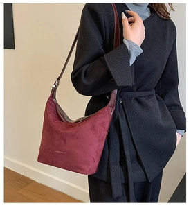 Close-up of stylish burgundy faux suede shoulder bag with elegant leather strap and textures