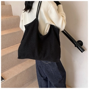 Detail of black faux fur tote bag with leather straps on model in minimalist setting