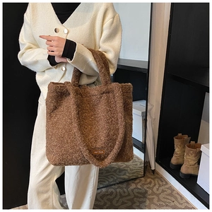 Detail of brown plush tote bag featuring soft fleece texture and leather logo tag label