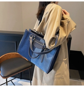 Detail view of contrast color denim tote bag showing leather handles and silver hardware