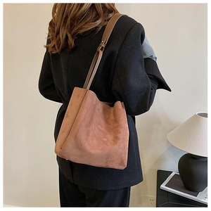 Détail d'un sac fourre-tout en daim marron avec bandoulière réglable dans une pièce minimaliste