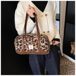 Detail shot of leopard print plush bowling bag with brown leather handles and logo label