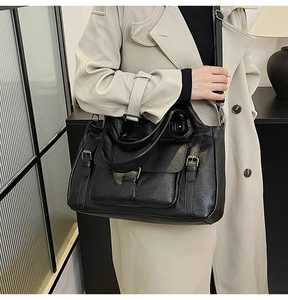 Close-up of black leather tote bag with decorative buckle and large front pocket detail