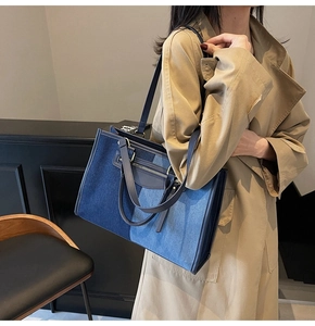 Detail of color-block denim tote bag showing patchwork fabric and double handle design