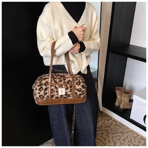 Detail shot of leopard print plush handbag with brown leather handles and brand logo