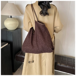 Detail view of large brown textured tote bag with leather handles shown on a model