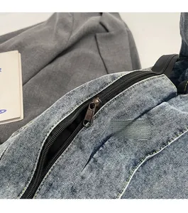 Close-up of smooth metal zipper and yellow stitching on blue washed denim tote bag