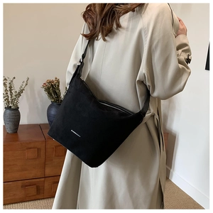Detail showing soft suede texture and silver metal zipper on the black fashion shoulder bag