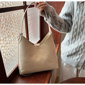 Detail of a large cream PU leather tote bag featuring elegant gold chain accents and strap