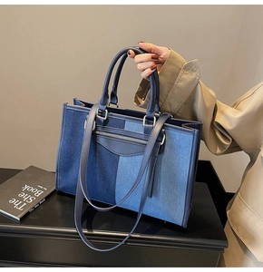 Detail of color-block denim tote bag showing blue patchwork textures and leather handles