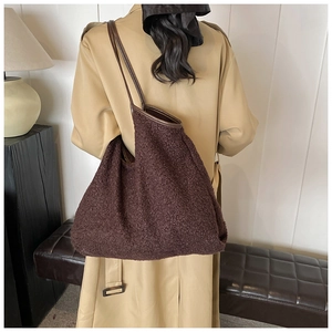 Detailed view of dark brown plush tote bag with slim leather handles and textured trim