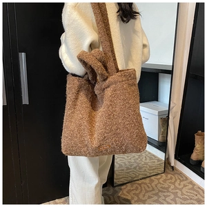 Detailed close-up of brown fuzzy fleece tote bag with knotted strap and small leather logo