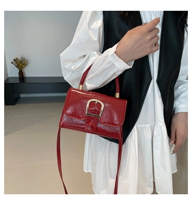 Dettaglio di una borsa in pelle verniciata bordeaux con fibbia in metallo dorato