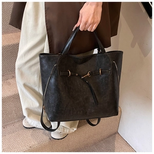 Detail of vintage oil-wax leather tote showing texture, dual handles and gold buckles