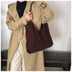 Detailed view of dark brown textured fleece tote bag with leather piping on model's shoulder