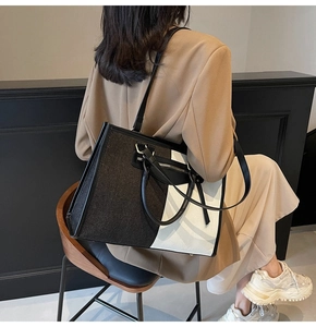 Detail of a large contrast canvas tote bag with leather straps and front zipper pocket