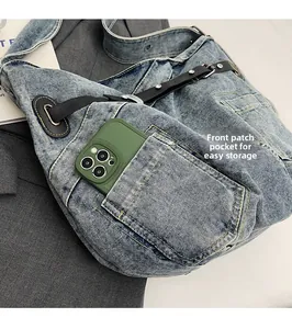 Detail of denim crossbody bag showing front pocket storage with a smartphone