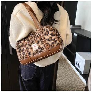 Detailed view of large leopard print plush shoulder bag featuring PU handles and brand label