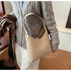 Detail of beige matte PU leather tote with wide strap and gold chain on model