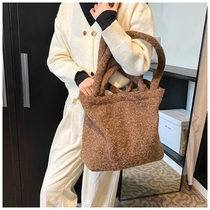 Detail shot of brown plush faux shearling tote bag featuring a leather patch and fuzzy texture