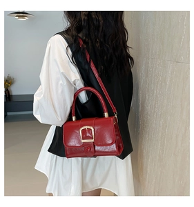 Borsa a mano moderna in vernice rossa con fibbia dorata indossata da una modella