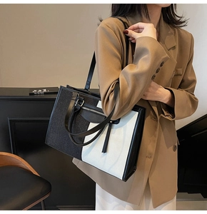 Side view of large color-block tote bag in black and white canvas with leather trim