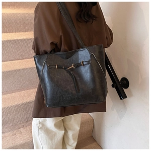Macro shot of a dark gray oil-wax leather tote bag with decorative side zippers on stairs