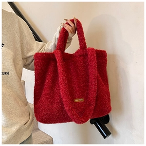 Detail of red fuzzy tote bag with leather tag showing plush texture and spacious design