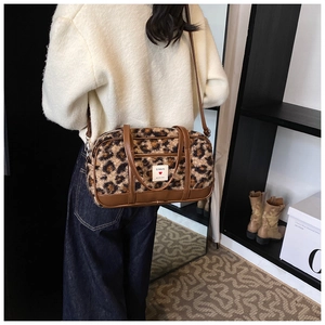 Detail of leopard print plush handbag with brown leather handles and adjustable strap