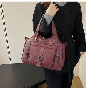 Detail view of burgundy PU leather tote bag with decorative metal buckles and front pocket