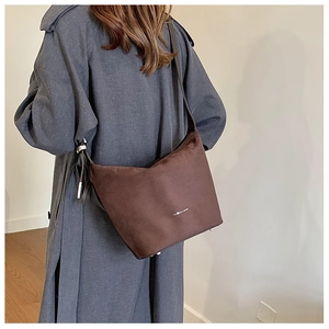 Detail of soft dark brown suede hobo bag worn by model showing large capacity and texture