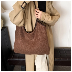 Detail of brown fuzzy fleece tote bag with dark leather straps on a trench coat model