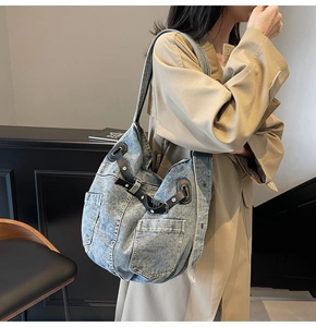 Detail of blue denim hobo bag featuring cargo pockets and adjustable black leather drawstring