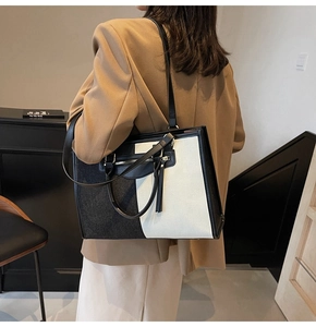 Detail of black and white canvas tote bag with leather trim on model in blazer
