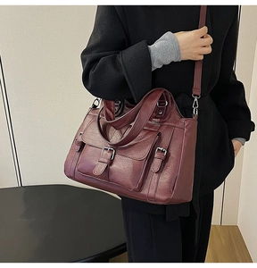 Detail of burgundy PU leather tote bag with silver buckle pocket on a black coat