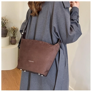Detail of dark brown bucket bag featuring silver bottom studs and fashion logo print