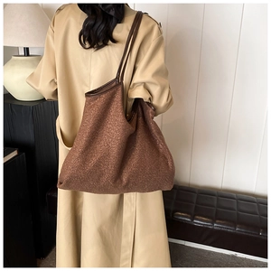 Close-up of brown plush tote bag with leather straps on a model in a minimalist room