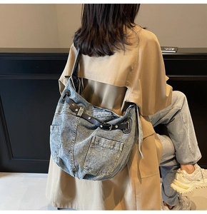 Detail of a large denim shoulder bag with retro utility pockets and brown leather straps