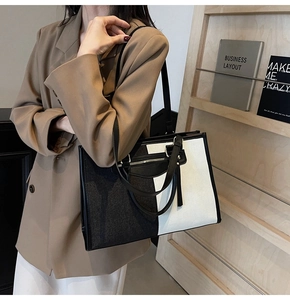 Detail of minimalist contrast tote bag featuring front tassel zipper and synthetic leather texture