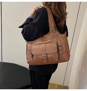 Brown faux leather tote bag with functional pockets shown worn over the shoulder